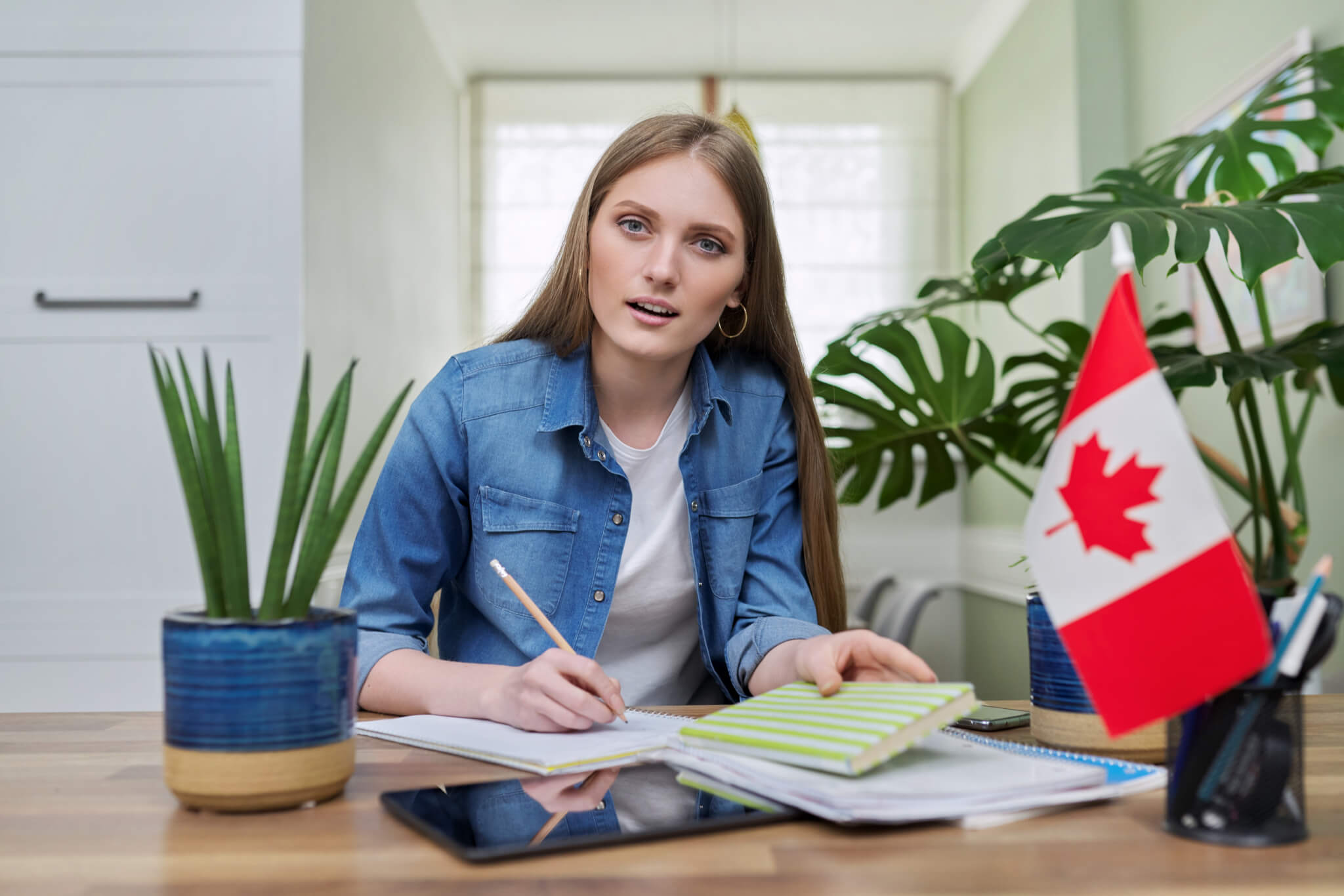 online-training-female-teenager-sitting-at-home-looking-at-webcam-canadian-flag-on-table